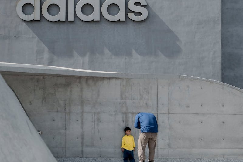 father and son taking photos under a huge brand name sign